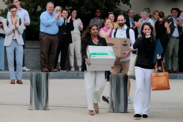 Recently laid off U.S. State Department employees carry boxes out of the Harry S. Truman Federal Building.