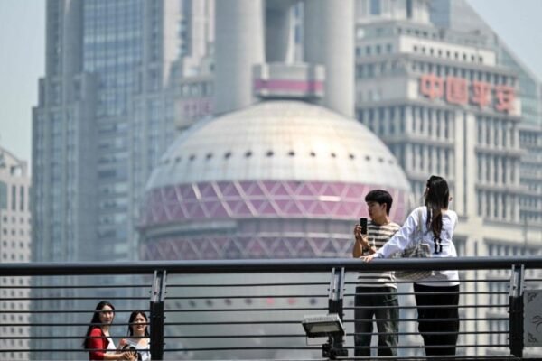 People are seen on The Bund promenade along the Huangpu River in Shanghai, with the city's financial district in the background. AFP