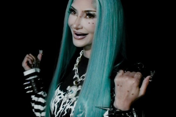 Kim Kardashian in a Halloween costume with blue hair and facial piercings.