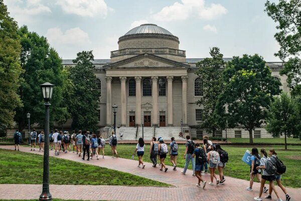 A line of students walk on the campus of the University of North Carolina
